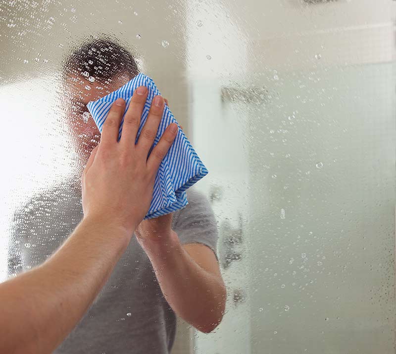 homem limpando espelho com pano azul