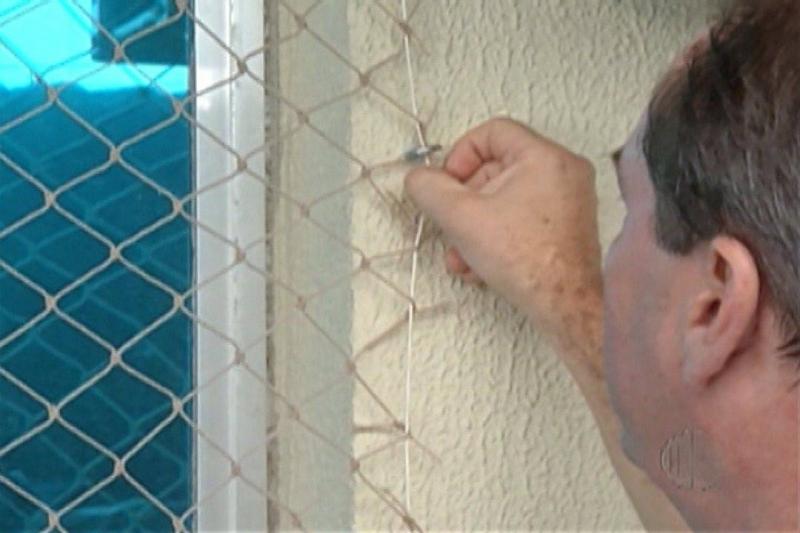 homem instalando rede de proteção em janela