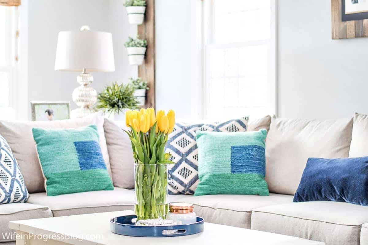sala com sofá branco e almofadas em tons de verde e azul