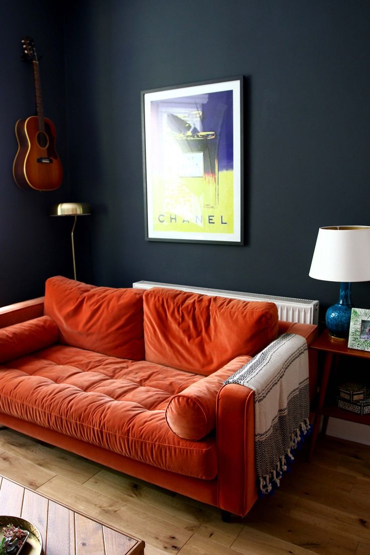 sala de estar com sofá laranja e parede preta