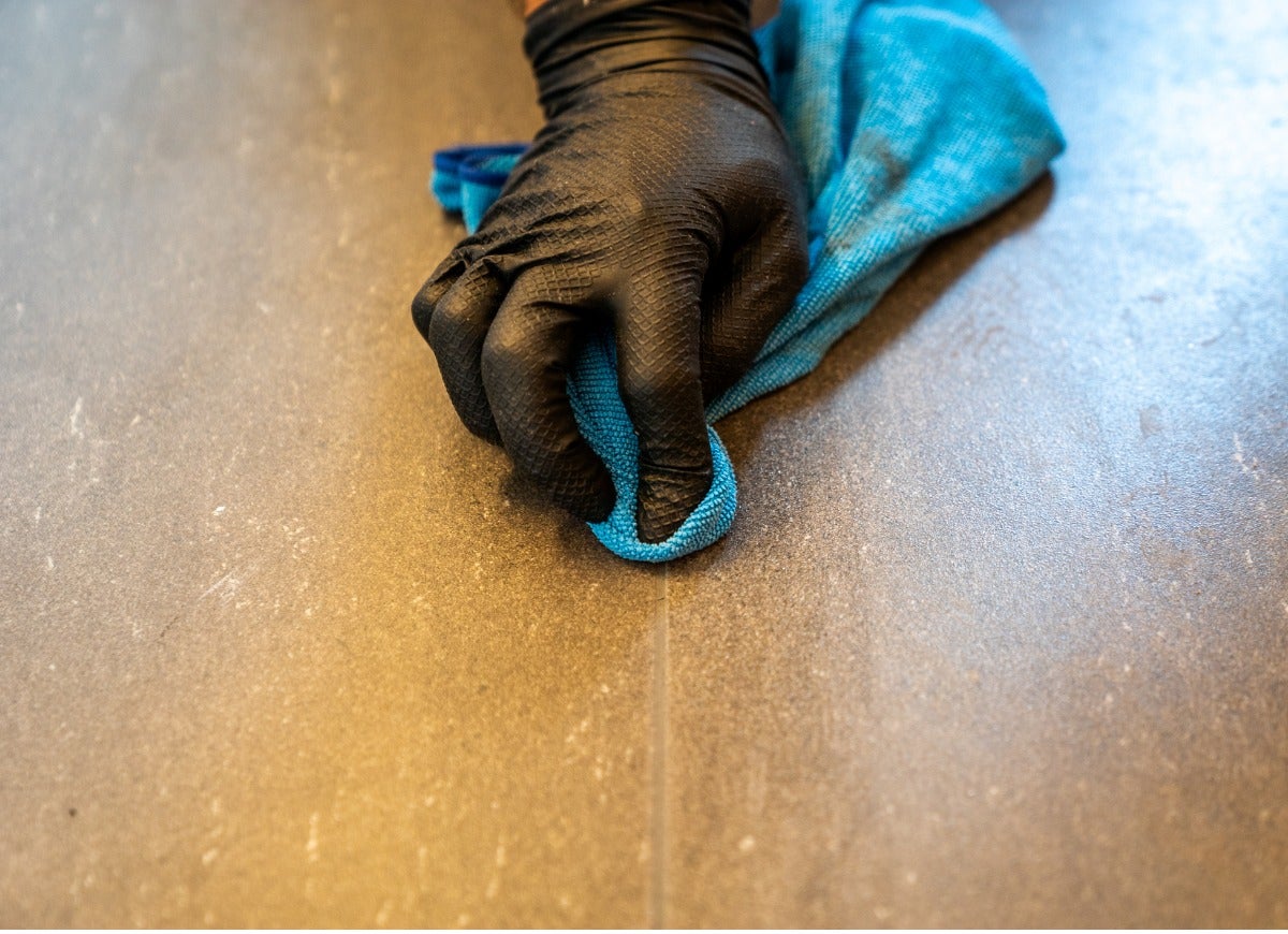 mão com luva preta fazendo limpeza de piso