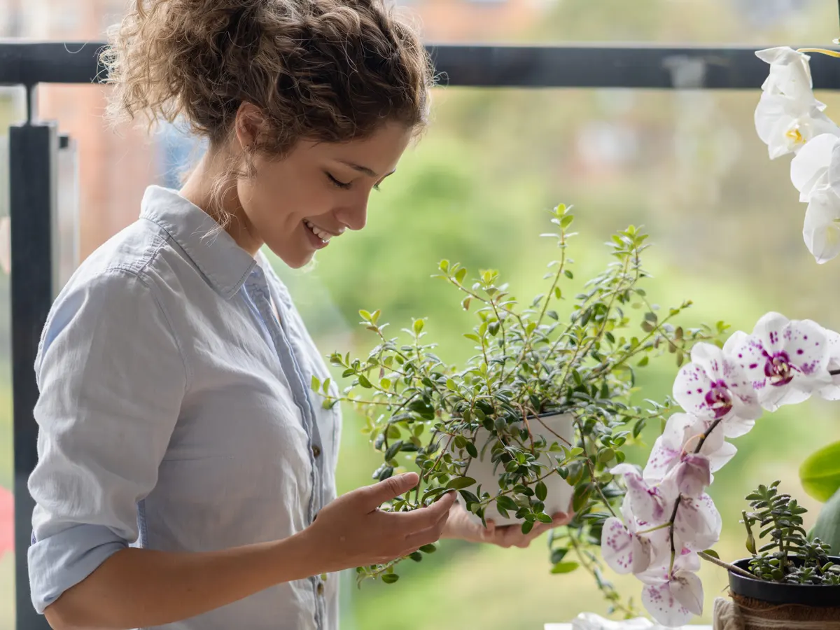 mulher sorrindo e segurando vaso com planta