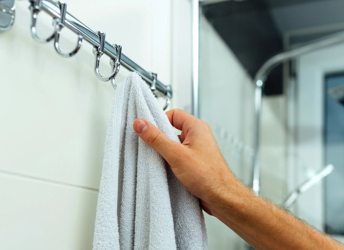 pessoa pegando toalha no banheiro