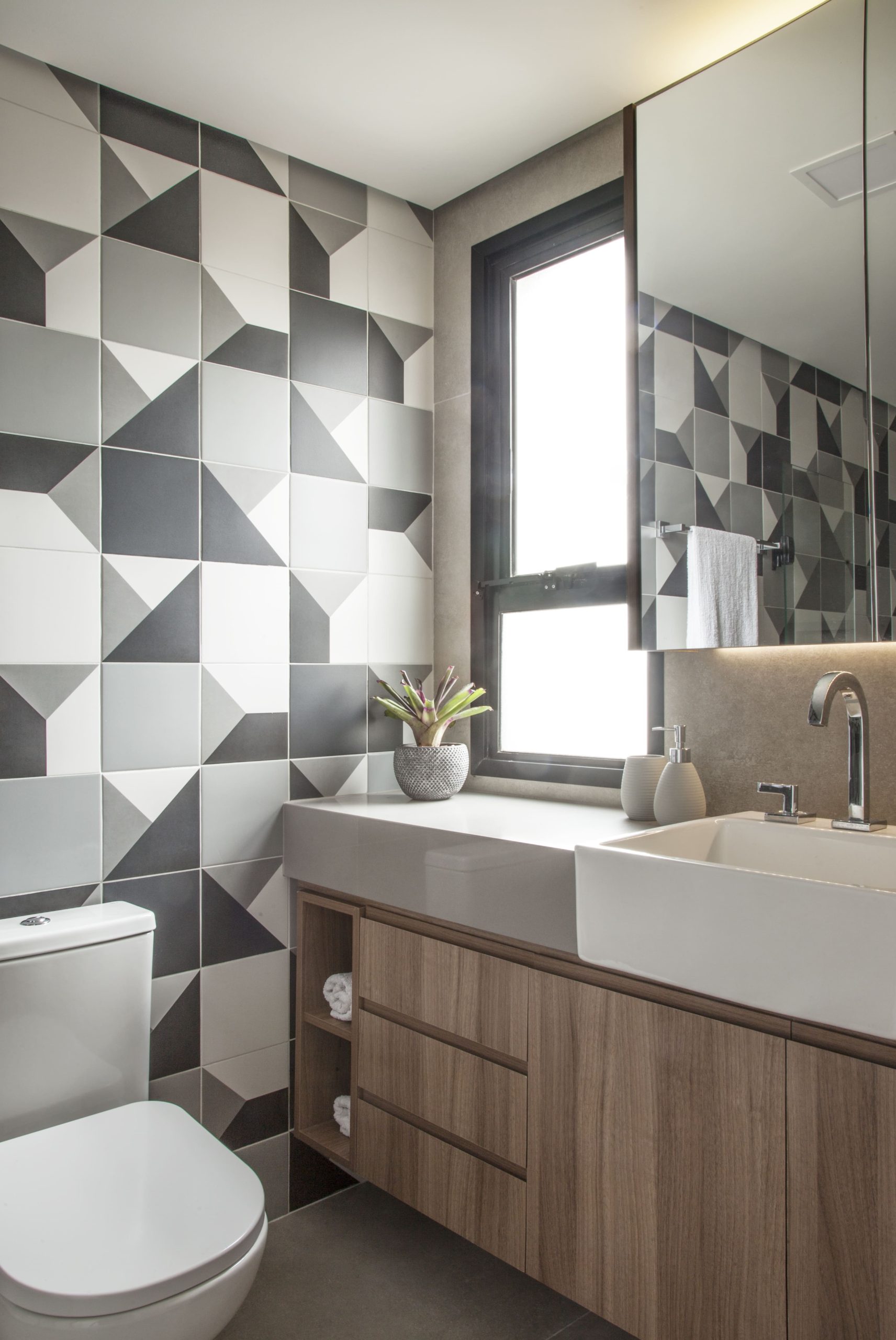 banheiro com piso de porcelanato cinza e revestimentos cerâmicos com vários tons de cinza