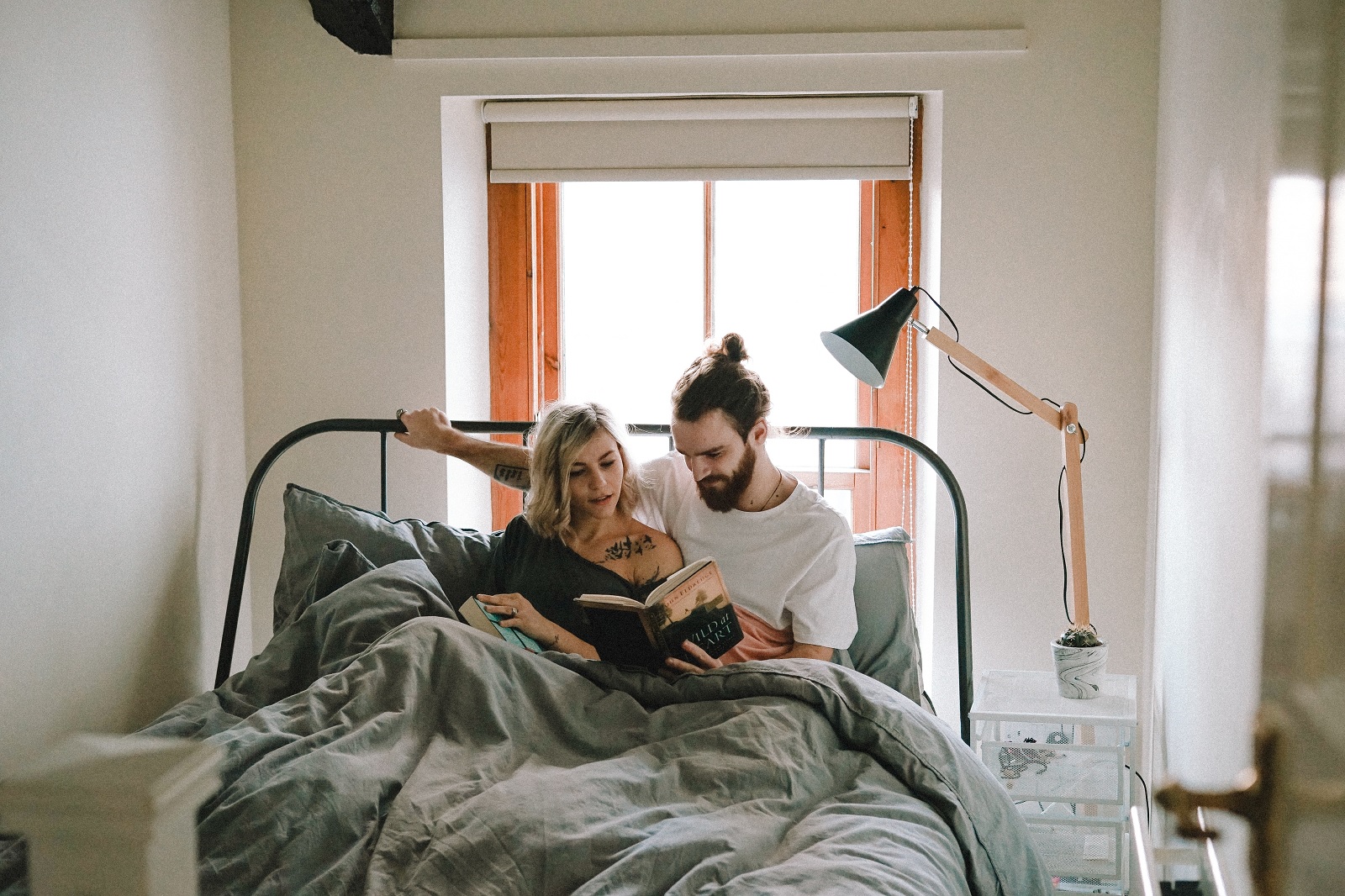 casal sentado na cama lendo livro