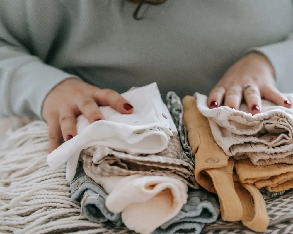 mulher organizando roupas de bebê