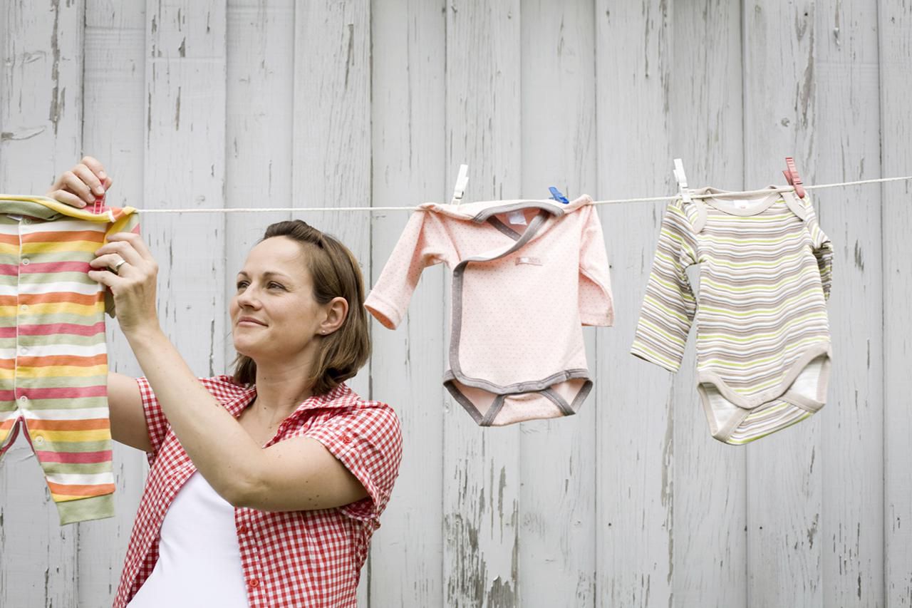 mulher pendurando roupas de bebê no varal