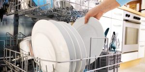 pessoa colocando pratos em máquina de lavar louça