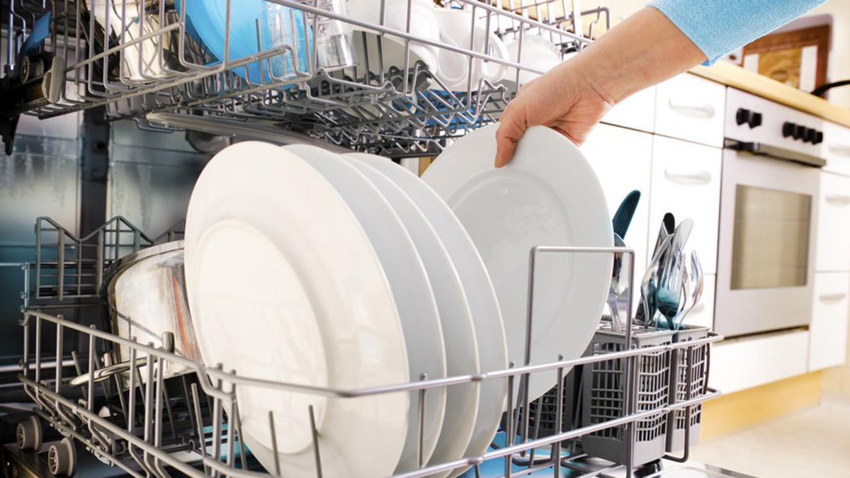 pessoa colocando pratos em máquina de lavar louça
