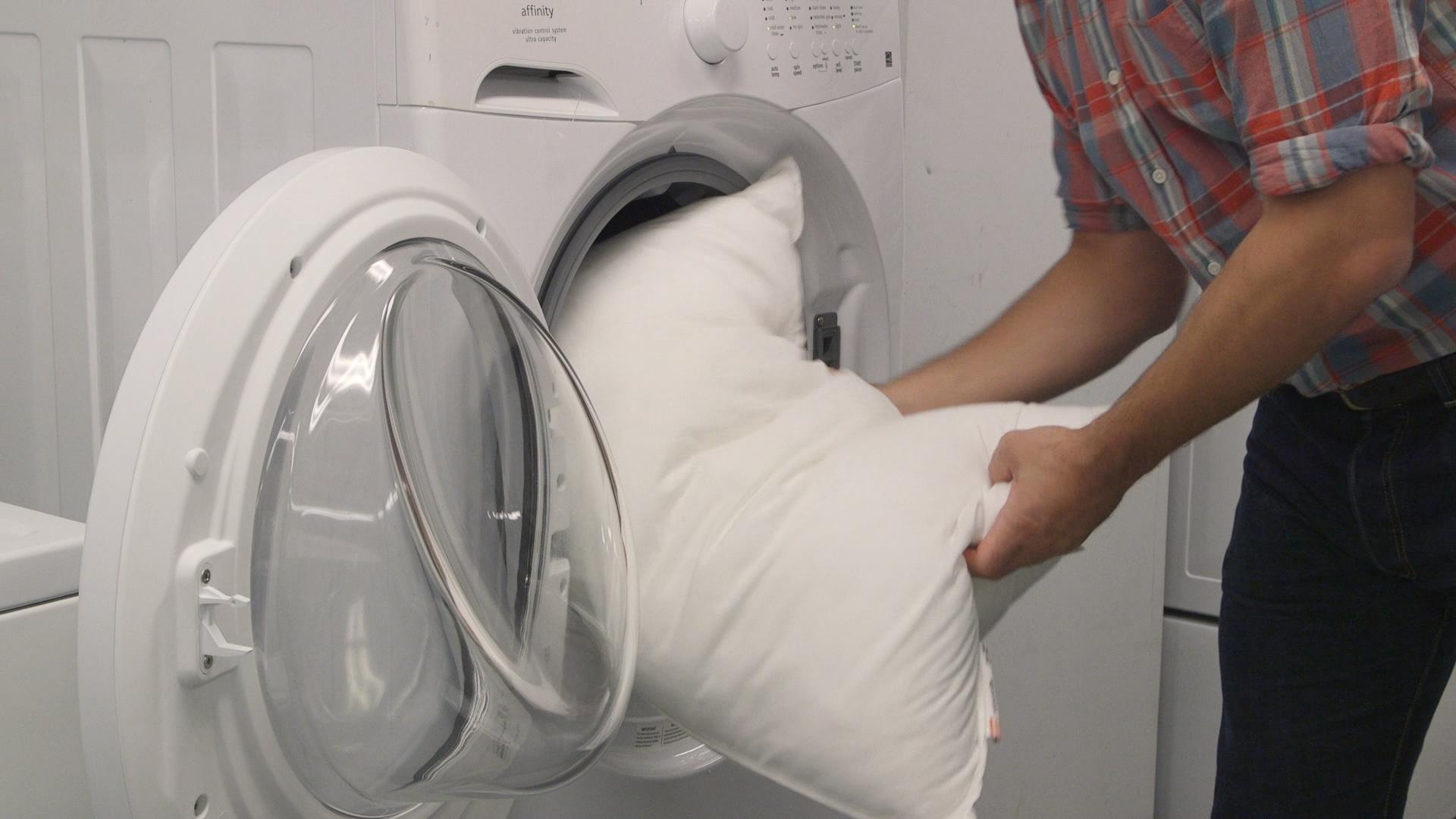 pessoa colocando travesseiro em máquina de lavar