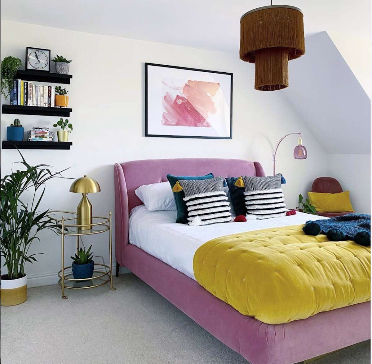 quarto com paredes brancas com cama rosa e colcha amarela