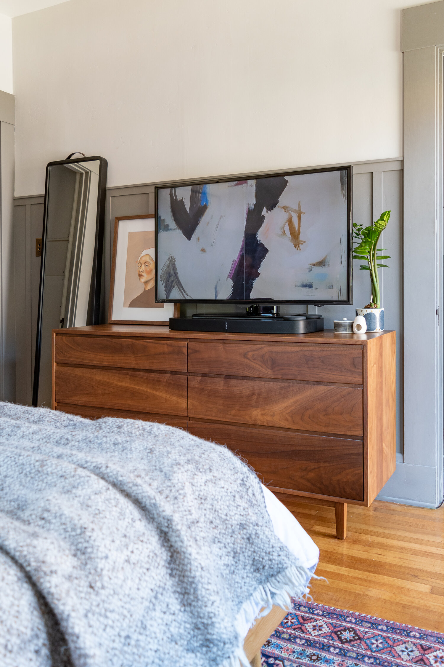 televisão sobre móvel em frente à cama