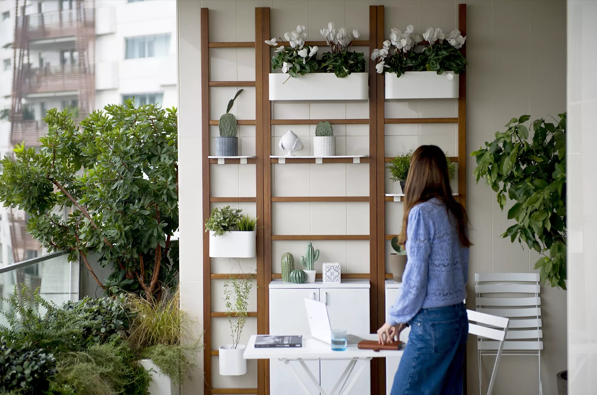 mulher em sacada com jardim vertical e mesa para home office