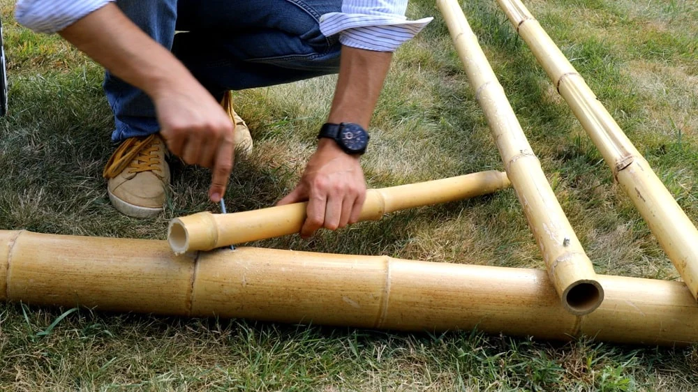 pessoa cortando vara de bambu