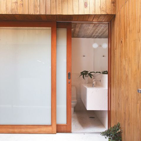 banheiro com porta de madeira e vidro com pelicula