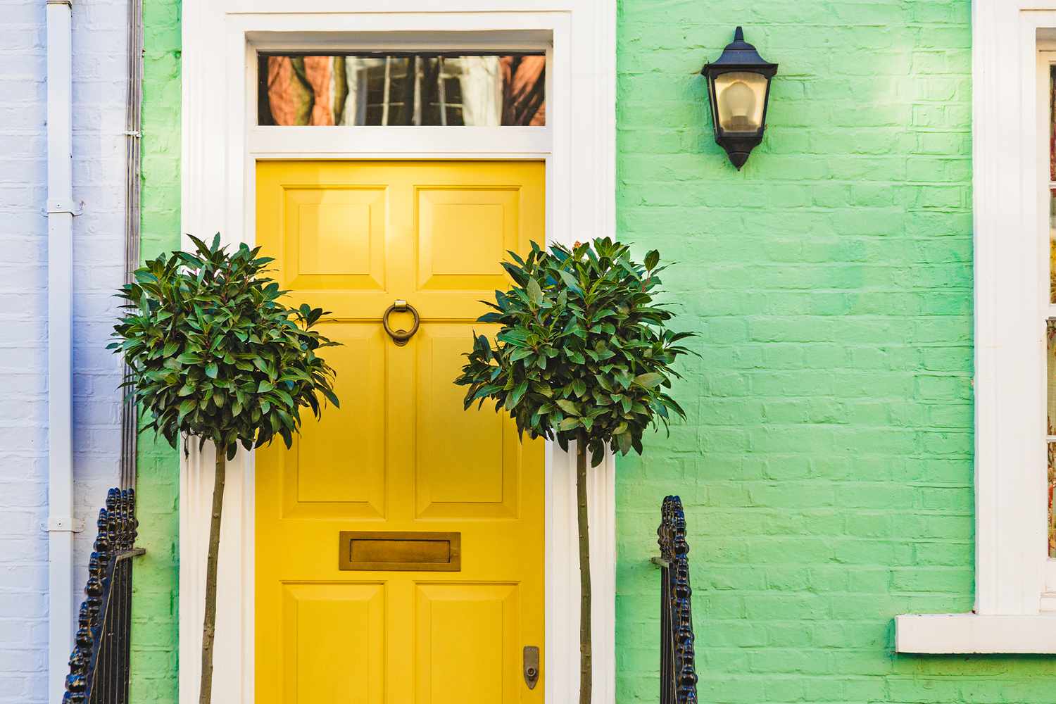 porta da frente em tom amarelo em casa verde